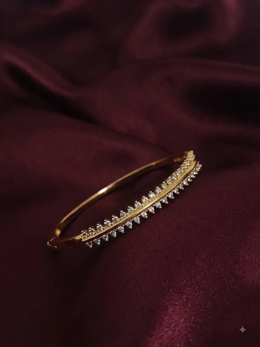 A gold-plated kada set with a row of crystals, on oxblood satin