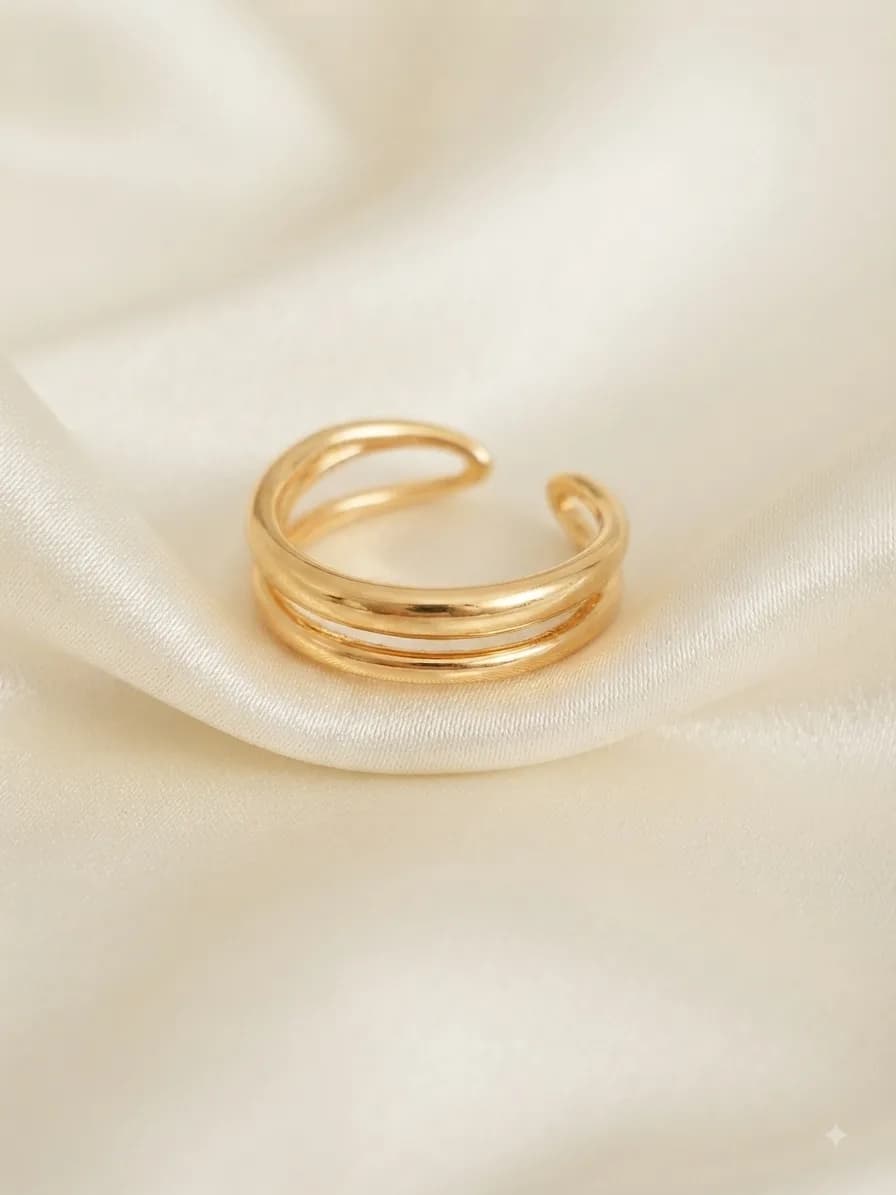 A wide gold-plated ring built from three stacked open bands, on ivory satin