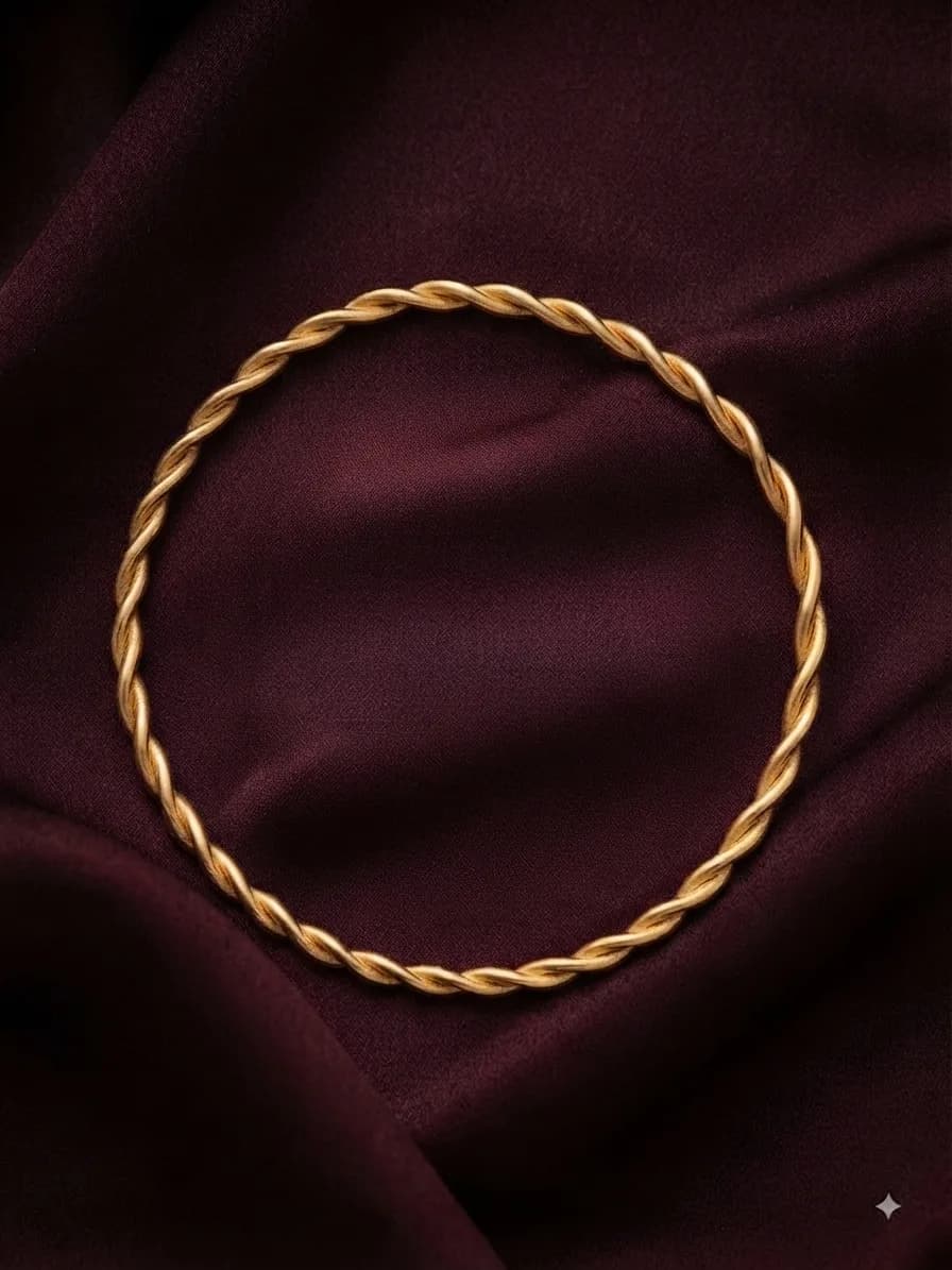 A gold-plated bangle twisted like rope, on oxblood satin