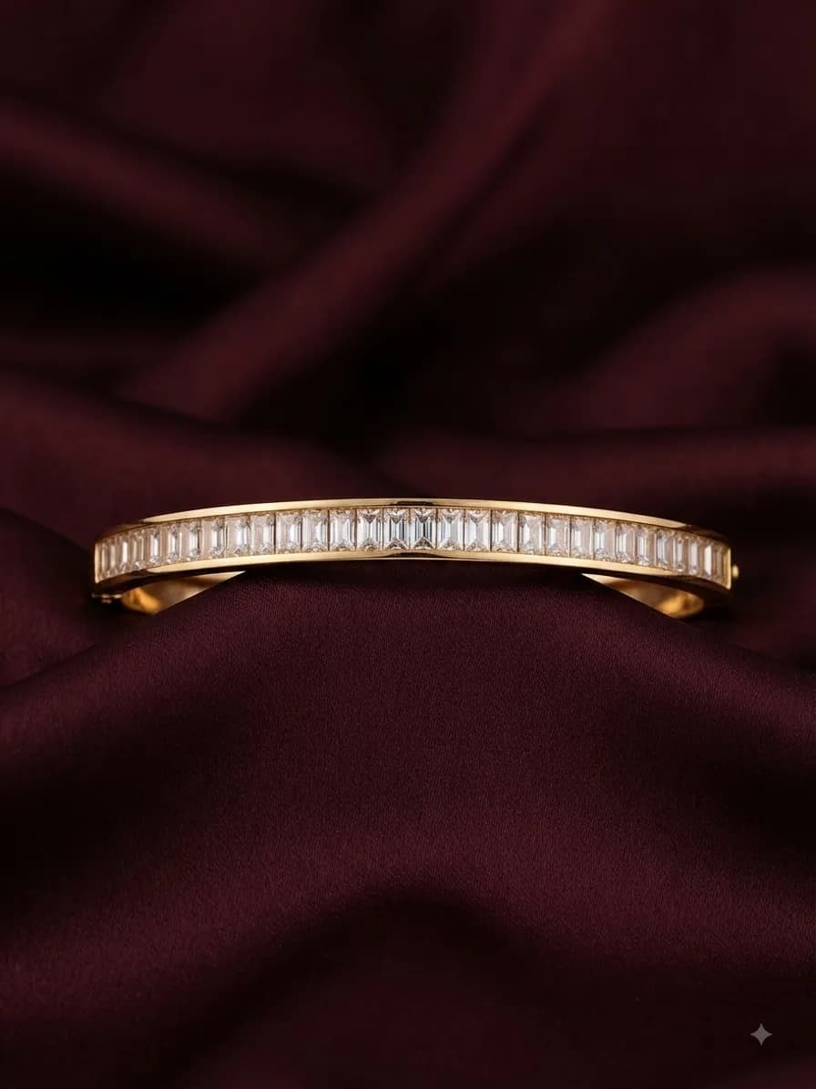 A gold-plated bangle channel-set with a line of clear baguette stones, on oxblood satin