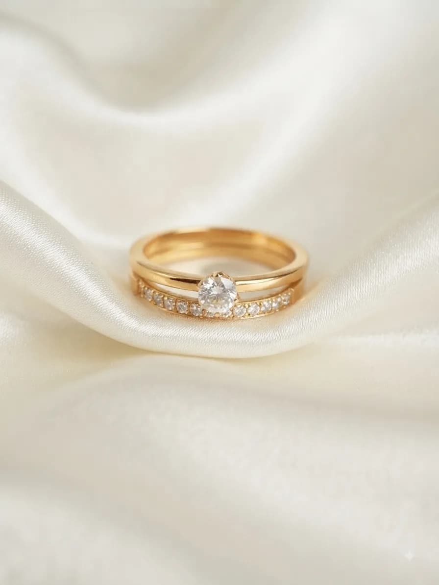 A gold-plated band holding a clear heart-shaped stone above a pavé band, on ivory satin