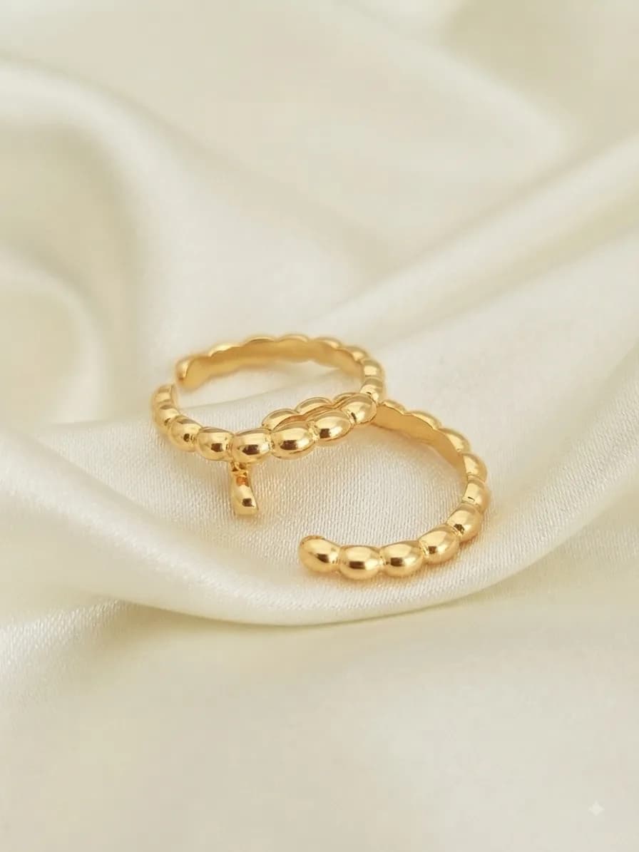 Two gold-plated bands with a beaded, bubbled surface, on ivory satin
