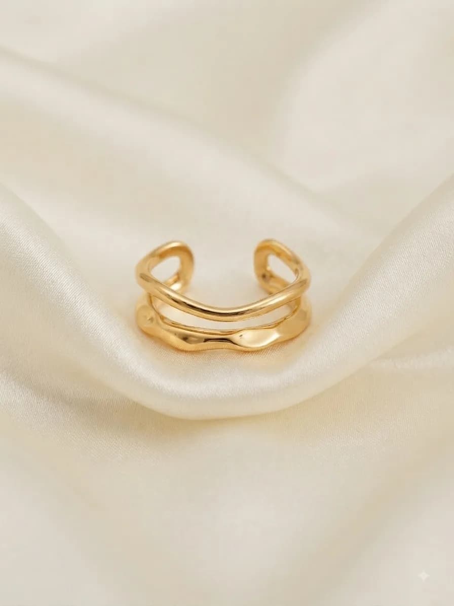An open gold-plated ring with a wave running between its double band, on ivory satin