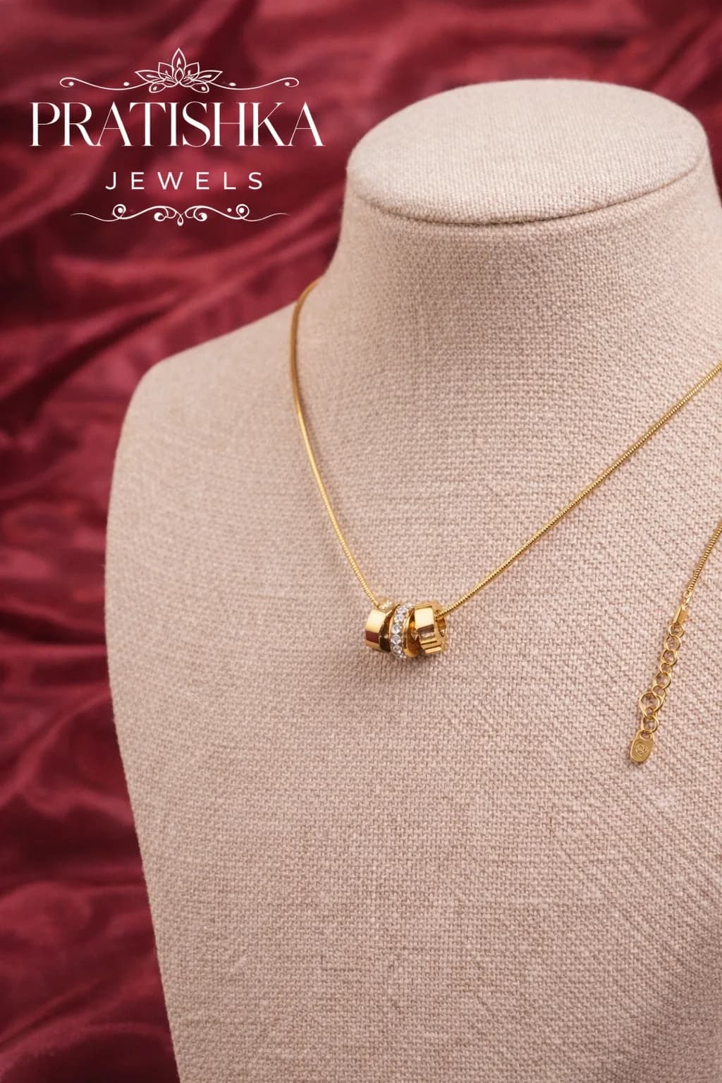 A gold-plated chain gathered through a cluster of interlocking rings, displayed on a linen bust form
