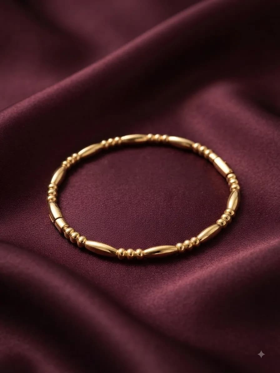 A gold-plated bangle broken up by ridged segments, on oxblood satin