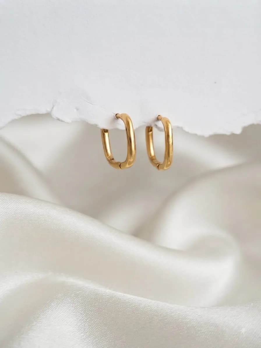 A pair of small rectangular gold-plated hoops on ivory satin