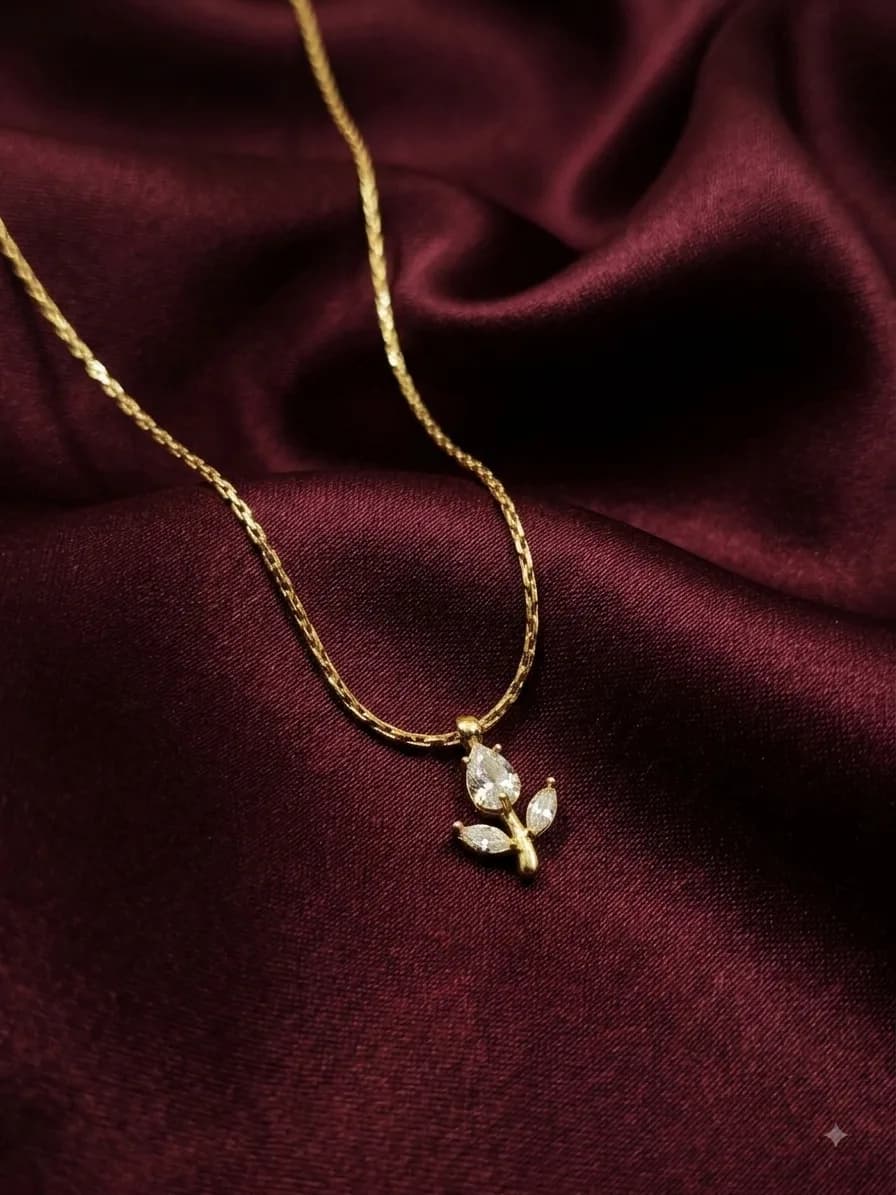 A gold-plated chain with a pendant of clear marquise-cut stones set as a tulip, on oxblood satin